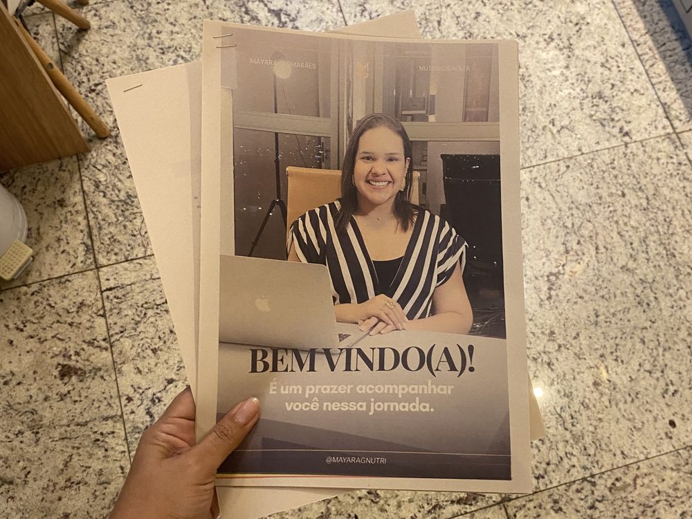 Material impresso de boas-vindas com a foto da Mayara sorrindo